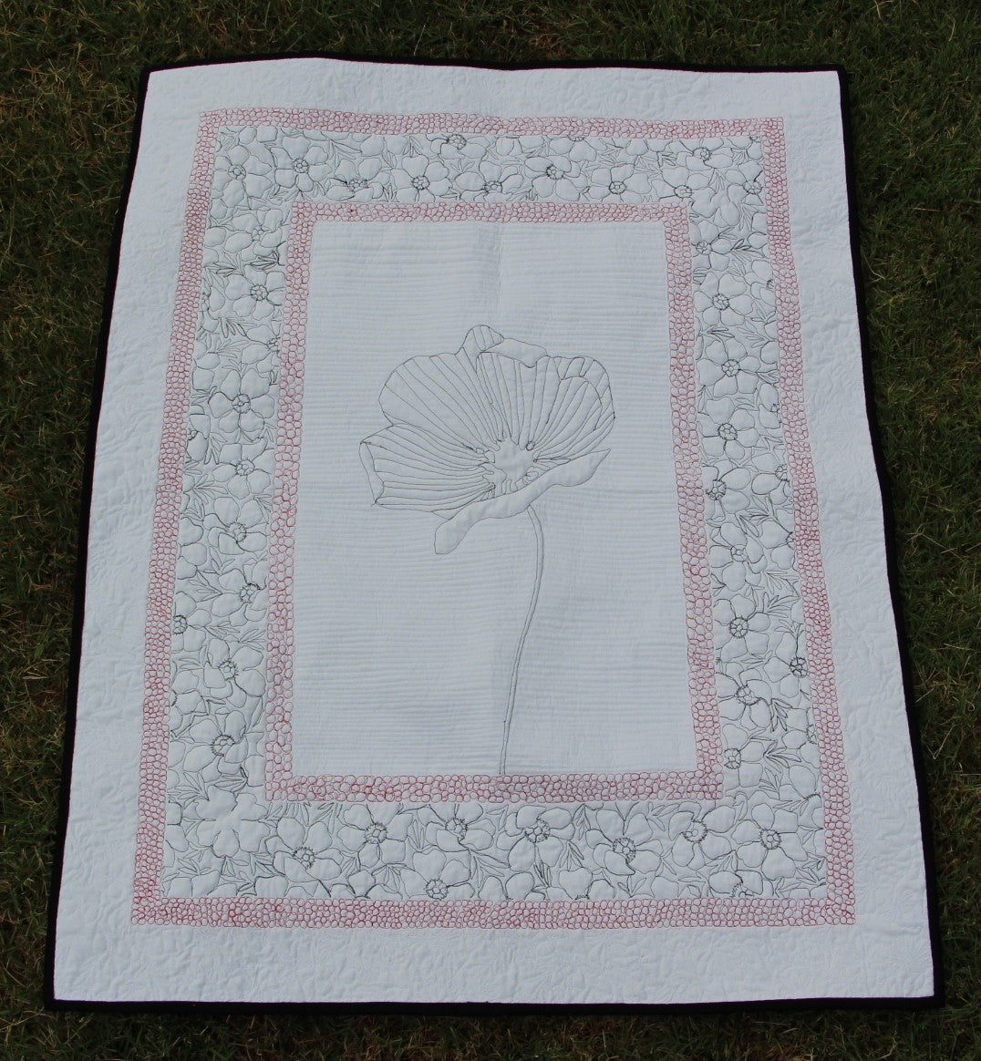 Back of Poppy wall hanging showing quilting. Stitched so that poppy and surrounding boarders are visible.